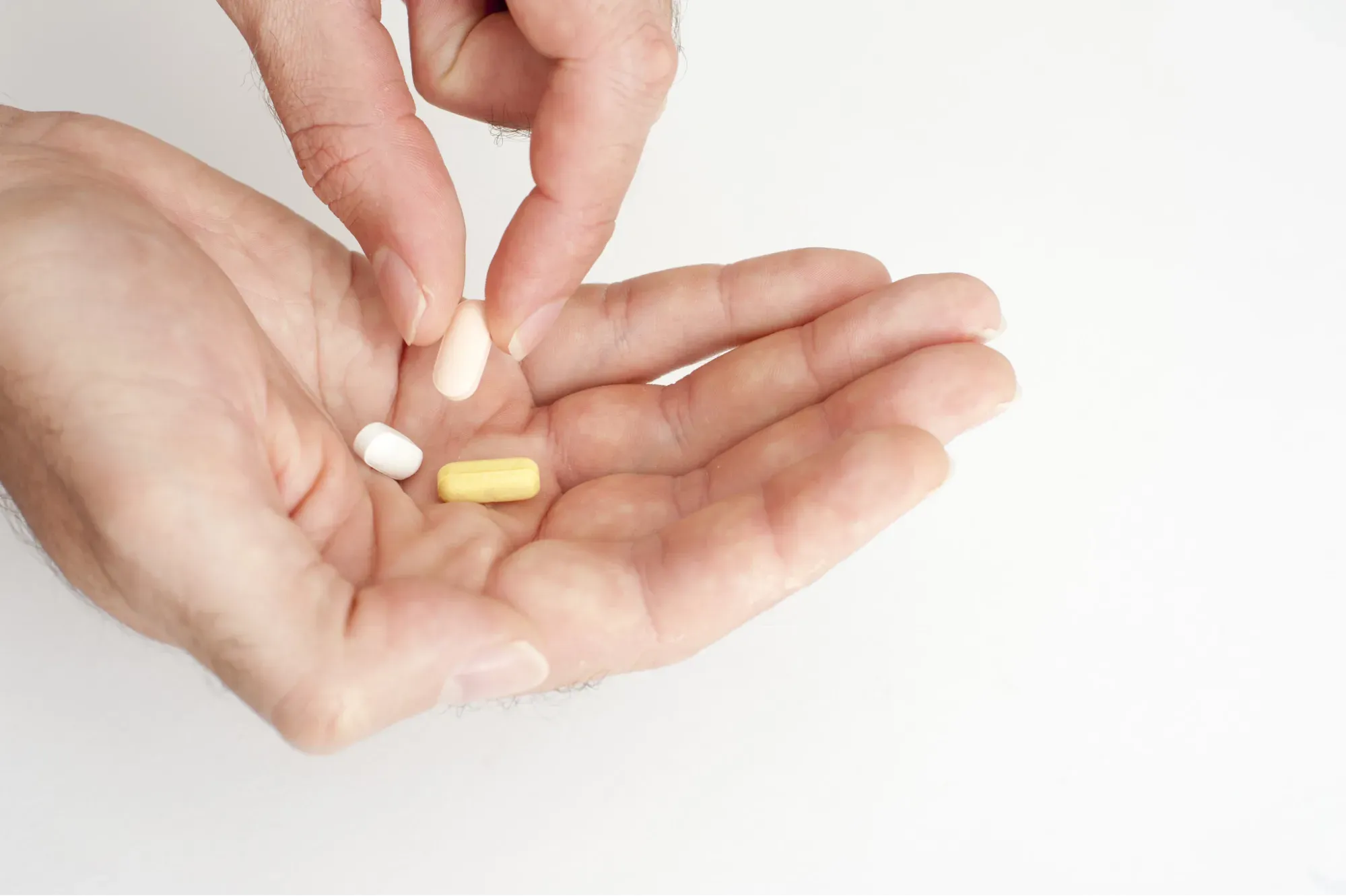 Mão segurando comprimidos, representando os medicamentos usados no tratamento