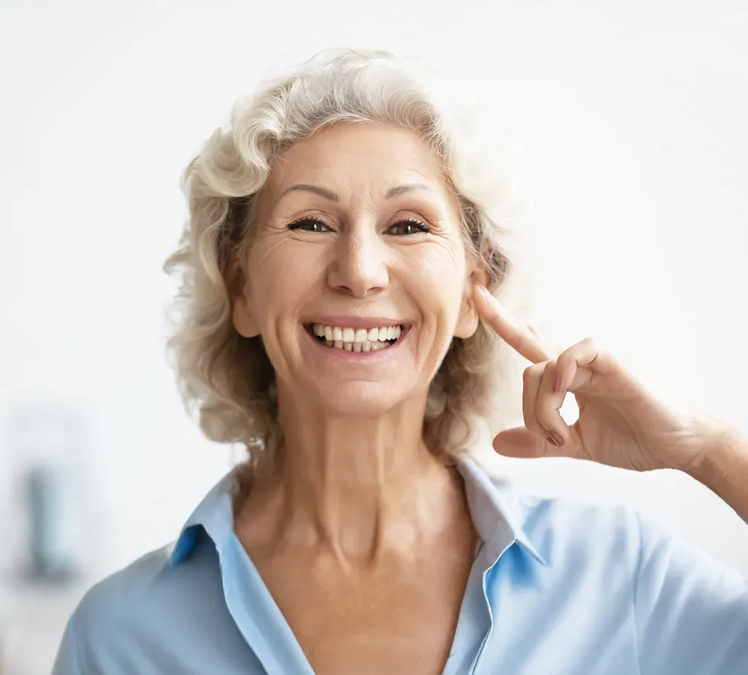 Mulher sorrindo e apontando para o próprio ouvido